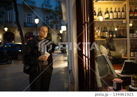 Woman holding coffee cup on nighttime city street 134961925