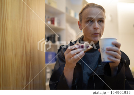Woman enjoying coffee and pastry indoors Woman enjoying coffee and pastry indoors 134961933