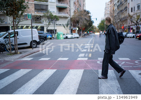 Person crossing city street at crosswalk 134961949