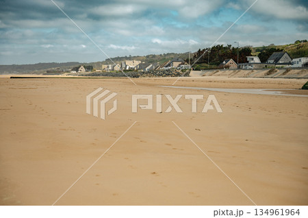 A wide view of Omaha Beach's peaceful shoreline in Normandy, France. Once a historic World War II landing site, the beach now offers a calm and reflective coastal landscape. 134961964