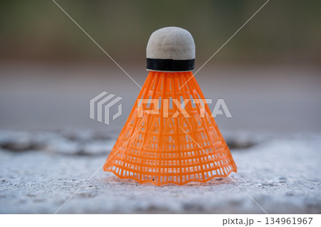Orange plastic shuttlecock on rough stone ground 134961967