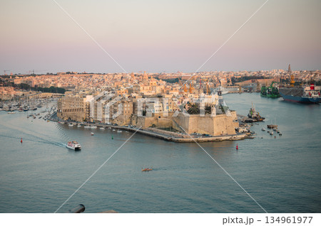 A stunning panoramic view of Birgu Port as seen from a Valletta vantage point, showcasing historic architecture, docked boats, and the scenic Maltese coastline. A stunning panoramic view of Birgu Port as seen from a Valletta vantage point, showcasing historic architecture, docked boats, and the scenic Maltese coastline. 134961977