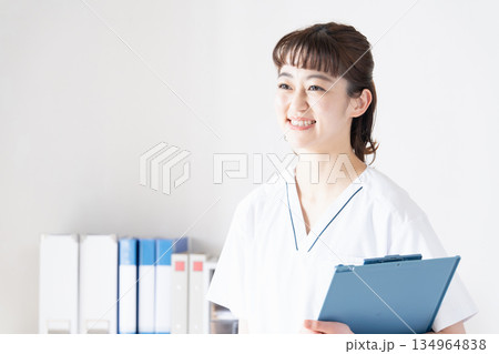 笑顔でファイルを持つ白衣の女性 笑顔でファイルを持つ白衣の女性 134964838