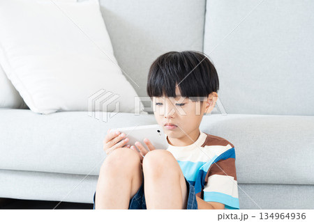 リビングでスマホで遊ぶ小学生男子 134964936