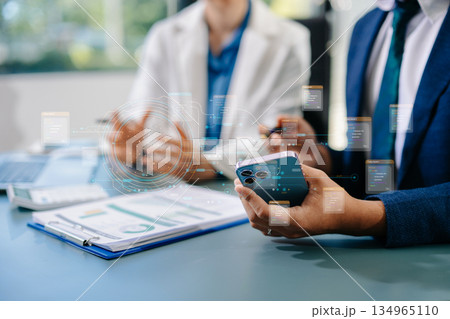 Business professionals using smartphone and holographic AI data interface to analyze digital information and innovate in office. Business professionals using smartphone and holographic AI data interface to analyze digital information and innovate in office. 134965110