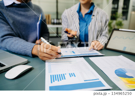 Businessman hand using laptop and tablet with social network diagram and two colleagues discussing data on desk as concept 134965250