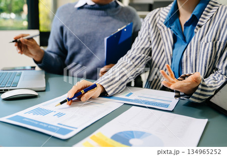 Business documents on office table with smart phone and calculator digital tablet and graph business with social network diagram and two colleagues discussing data working in the office 134965252