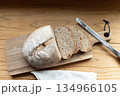 木のボードに乗ったスライスされた自家製カンパーニュとパン切り包丁 134966105