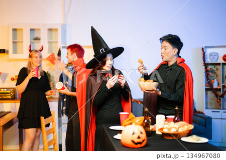 Joyful office Halloween party with coworkers in costumes, celebrating with drinks and laughter, fostering teamwork and festive spirit 134967080