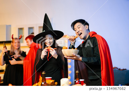 Joyful office Halloween party with coworkers in costumes, celebrating with drinks and laughter, fostering teamwork and festive spirit 134967082