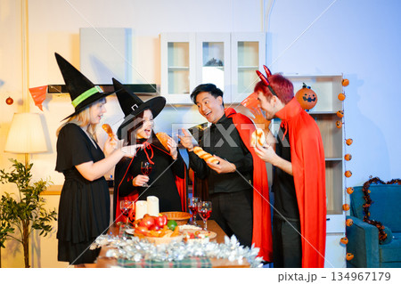 Halloween party react with surprise and laughter to spooky props like pumpkins and a ghost skeleton. Perfect seasonal fun, decor, and festive vibes. 134967179