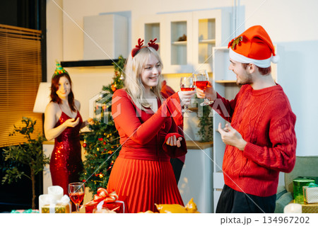 Group of cheerful friends enjoying Christmas celebration with gifts, food, and holiday decorations in a warm festive atmosphere. Group of cheerful friends enjoying Christmas celebration with gifts, food, and holiday decorations in a warm festive atmosphere. 134967202