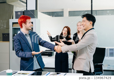 Successful business handshake with colleagues applauding, symbolizing teamwork, partnership, trust, and corporate achievement in a modern office 134967429
