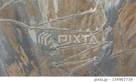Aerial view of winding dirt roads through rugged mountainous terrain 134967739