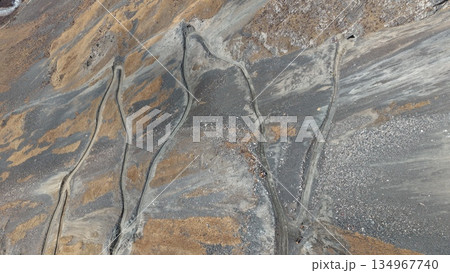 Aerial view of winding dirt roads through rocky mountainous terrain Aerial view of winding dirt roads through rocky mountainous terrain 134967740