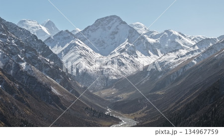 Majestic snow-capped mountains towering over serene valley landscape Majestic snow-capped mountains towering over serene valley landscape 134967759