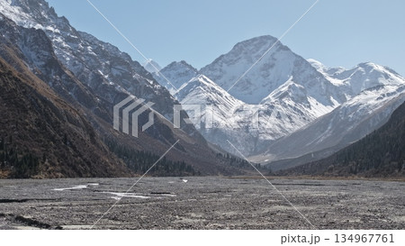 Majestic snow-capped mountains towering over rocky valley landscape Majestic snow-capped mountains towering over rocky valley landscape 134967761