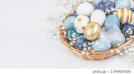 Blue and gold Easter eggs in wicker basket with copy space on white background Blue and gold Easter eggs in wicker basket with copy space on white background 134969300