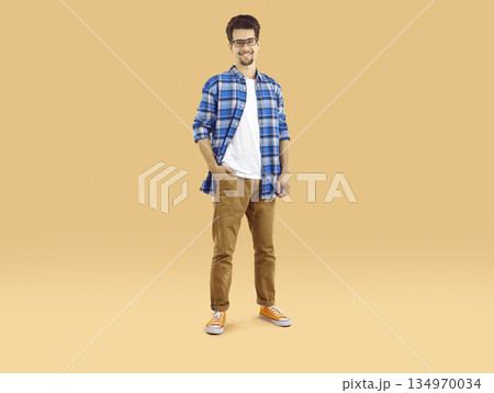 Portrait of a happy male student in glasses and casual clothes standing on a studio background Portrait of a happy male student in glasses and casual clothes standing on a studio background 134970034