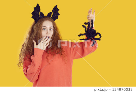 Funny woman imitating scared look while holding scary halloween decorative spider. Funny woman imitating scared look while holding scary halloween decorative spider. 134970035