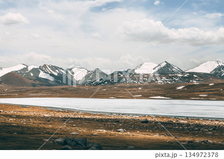 Frozen lake with snowy mountains in the background. Winter landscape Frozen lake with snowy mountains in the background. Winter landscape 134972378