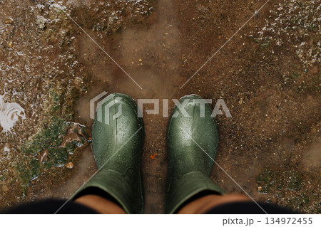 POV shot of person with rain boots standing on wet ground during rainfall, with raindrops in Rainy season POV shot of person with rain boots standing on wet ground during rainfall, with raindrops in Rainy season 134972455