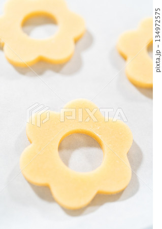 Top view of a baking sheet lined with unbaked flower-shaped sugar cookies. These will form the base for Easter Cookie Sandwich with Raspberry Buttercream. Top view of a baking sheet lined with unbaked flower-shaped sugar cookies. These will form the base for Easter Cookie Sandwich with Raspberry Buttercream. 134972575