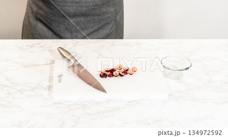 Fresh cranberries are finely chopped on a cutting board, prepared for adding to the cranberry buttercream in the lemon spritz cookie recipe. Fresh cranberries are finely chopped on a cutting board, prepared for adding to the cranberry buttercream in the lemon spritz cookie recipe. 134972592