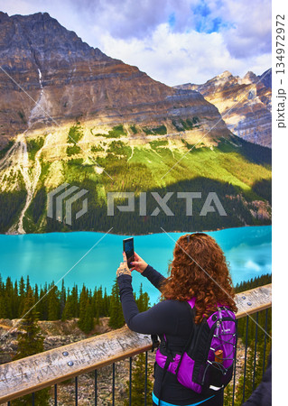 Tourist Hiker Taking Photo of Turquoise Lake and Mountains in Banff National Park 134972972