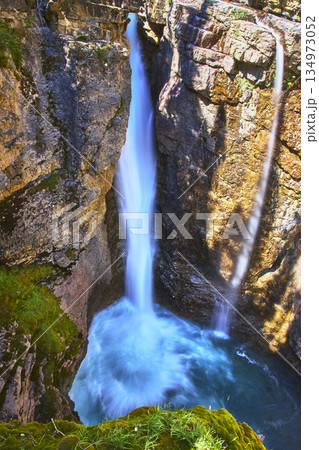 Waterfall Plunging Into Rocky Canyon With Lush Moss And Turquoise Pool 134973052