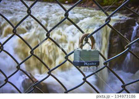 Padlock on Chain Link Fence with Blurred Waterfall and Flowing Water 134973186