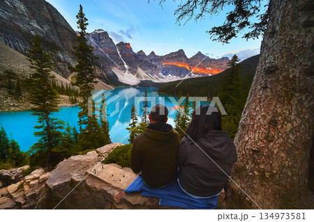Lake Moraine Sunrise with Tourists Overlooking Blue Water and Majestic Mountains 134973581