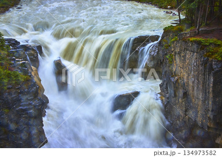 Sunwapta Falls Rushing Water Over Rocky Cliffs and Lush Forest in Jasper Canada Sunwapta Falls Rushing Water Over Rocky Cliffs and Lush Forest in Jasper Canada 134973582