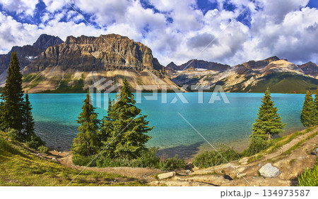 Panorama Turquoise Lake Water and Majestic Mountain Range with Evergreen Trees 134973587