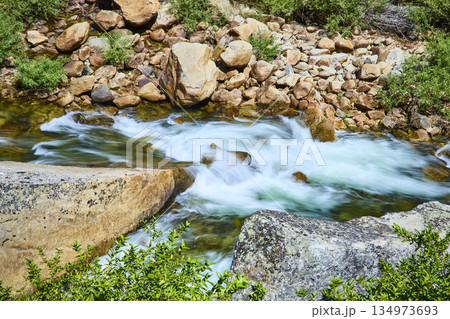 Rushing Merced River with Granite Boulders and Lush Greenery in Sunlight Rushing Merced River with Granite Boulders and Lush Greenery in Sunlight 134973693