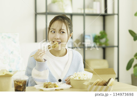 リビングでお弁当を食べる若い日本人女性 リビングでお弁当を食べる若い日本人女性 134973698