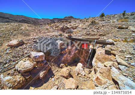 Abandoned Mine Entrance Rocky Desert Terrain and Warning Sign in Nevada 134973854