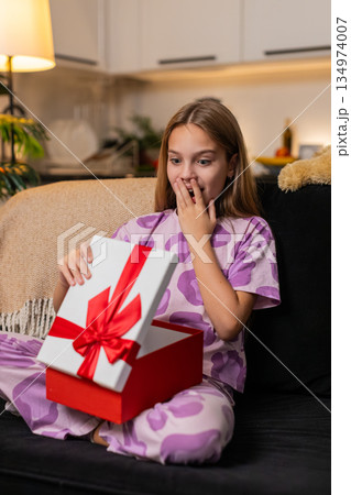 Teenager girl opens gift box joyful surprise sees wished toy inside smile excited reaction big smile 134974007