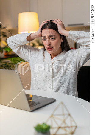 Young woman at night home plays online game on laptop lose from online game or lottery feels upset Young woman at night home plays online game on laptop lose from online game or lottery feels upset 134974012