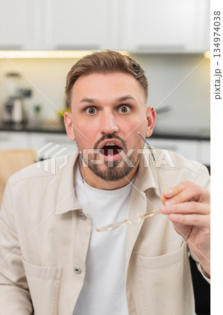 Young man removes glasses says wow happy and surprised after good news with bright smile wide eyes Young man removes glasses says wow happy and surprised after good news with bright smile wide eyes 134974038