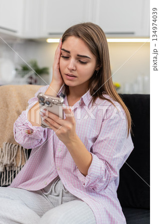 Young woman upset by game loss and job refusal sighs touches brow shakes head no holding smartphone Young woman upset by game loss and job refusal sighs touches brow shakes head no holding smartphone 134974039