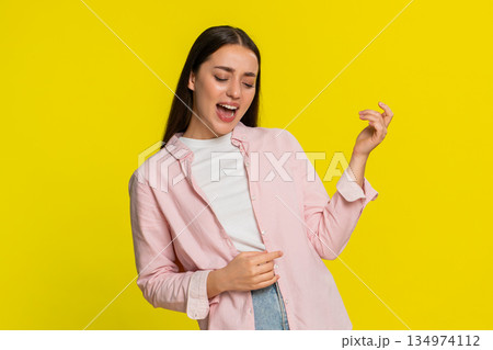 Young woman pretending to play guitar with expressive hand gestures enjoying music with passion joy 134974112