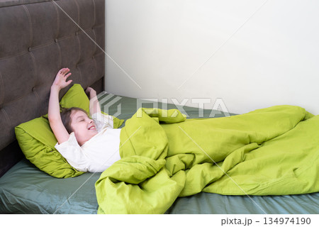 Happy little girl waking up in the morning. Child stretching in a comfortable bed 134974190