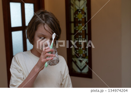 Young boy rinsing his mouth with water after brushing teeth. Morning dental hygiene routine Young boy rinsing his mouth with water after brushing teeth. Morning dental hygiene routine 134974204