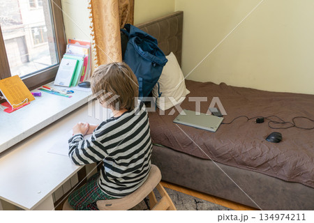 Boy doing homework at a desk in his bedroom. Student learning at home. Homeschooling concept 134974211