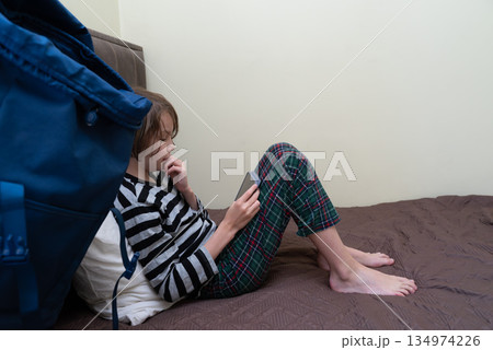 Child in pajamas using a smartphone on the bed. Young boy focused on a mobile device Child in pajamas using a smartphone on the bed. Young boy focused on a mobile device 134974226