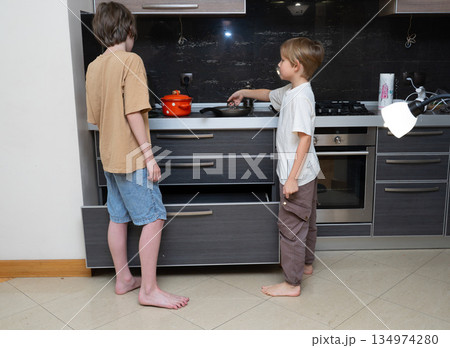 Two young brothers cooking together in a modern kitchen. Kids learning domestic skills at home Two young brothers cooking together in a modern kitchen. Kids learning domestic skills at home 134974280