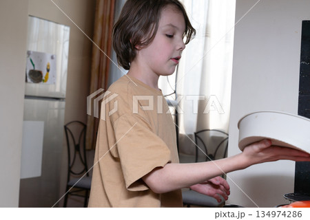 Focused young boy cooking in a home kitchen. Child helping with food preparation Focused young boy cooking in a home kitchen. Child helping with food preparation 134974286