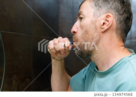Profile of a middle-aged man brushing his teeth. Daily dental care and oral hygiene routine Profile of a middle-aged man brushing his teeth. Daily dental care and oral hygiene routine 134974568