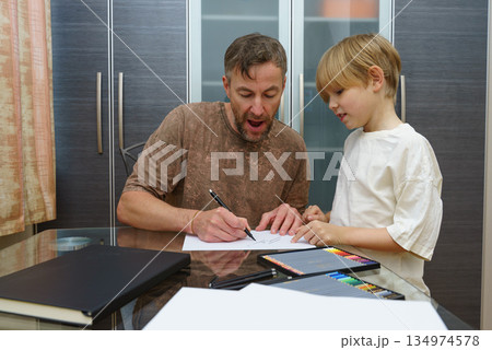 Dad and son drawing together at a desk. Homeschooling and parenting concept 134974578